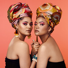 Image showing African fashion, makeup and portrait of women on orange background with accessory, makeup and beauty. Glamour, luxury and female people in exotic jewelry, traditional style and head scarf in studio