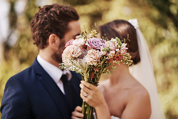 Image showing Flowers, wedding and a married couple behind a bouquet together after a ceremony of tradition outdoor. Love, marriage or commitment with a man and woman outside as husband and wife in matrimony