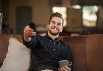 Image showing Relax, coffee and a man watching tv on a sofa in the living room of his home with a remote for streaming. Smile, tea and a happy young male person using a subscription service on his television