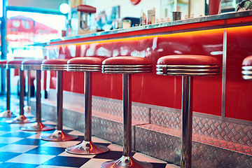 Image showing Trendy, vintage and retro interior in a diner, restaurant or cafeteria with funky decor. Booth, old school and chairs by a counter or bar in a groovy, vibrant and stylish old fashioned empty cafe.