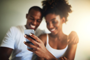 Image showing Hand, cellphone and texting in home with happy couple for communication, social media app and meme together. Black man, woman and smartphone in house with reading, online chat and watch funny video