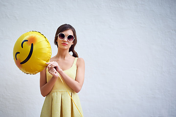 Image showing Woman, balloon and sunglasses by wall background in summer with emoji, fashion and mock up space for party. Gen z girl, event and portrait with icon, smiley and yellow dress for spring celebration