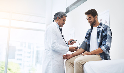 Image showing Healthcare, patient and doctor with blood pressure test, help and wellness checkup of person at hospital. Medicine, health care expert and Indian man in doctors office consulting medical professional