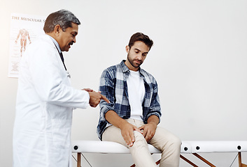 Image showing Healthcare, doctor and patient with knee pain in consultation for expert advice, information and discussion. Medicine, health care and Indian man in doctors office consulting medical professional.