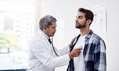 Image showing Healthcare, patient and doctor with stethoscope for checkup, help and wellness at hospital. Medicine, health care and heart expert with Indian man in doctors office consulting medical professional.