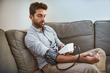 Image showing Hypertension, machine and man exam blood pressure in a home sofa or living room for medical or health test. Monitor, reading and person with equipment for chronic disease due to stress