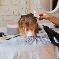 Image showing Hairdresser making a hair style to cute little girl.