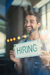 Image showing Man with hiring sign, cafe window with recruitment and job opportunity, happy waiter or barista in portrait. Small business, entrepreneur and male owner onboarding, advertising hire at coffee shop