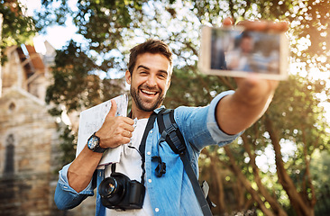 Image showing Happy man, tourist and thumbs up selfie outdoor in a city for travel with holiday memory, smile and happiness. Male person on adventure, journey with sign for vacation photo and freedom with backpack