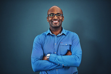 Image showing Business, black man and portrait with arms crossed in a studio feeling proud from auditor work. Blue background, smile and African employee with success and leadership vision with glasses and idea