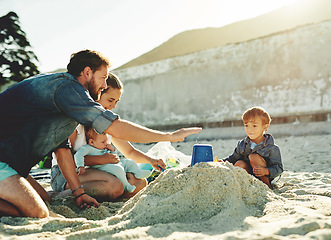 Image showing Sandcastle help, parents and children at the beach with bonding, love and support. Baby, mom and dad together with kids playing in the sun with happiness and smile by the ocean and sea with family