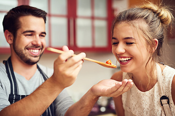 Image showing Food, man feeding a woman with spoon and in a kitchen of their home. Hungry or happiness, healthy relationship and happy people cooking preparing meal for lunch or dinner time in their house