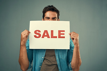 Image showing Man, hands and sale sign for advertising, marketing or branding against a grey studio background. Excited male person or model holding billboard or poster for sales, announcement or advertisement