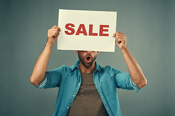 Image showing Man, hands and sale sign for advertising, marketing or branding against a grey studio background. Male person, surprise or discount holding board or poster for sales announcement or advertisement