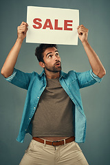 Image showing Man, hands and sale on poster for advertising, marketing or branding against a grey studio background. Male person or realtor holding board, sign or billboard for sales announcement or advertisement