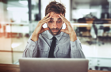 Image showing Businessman, laptop and headache in stress, anxiety or burnout from debt at the office desk. Frustrated man person or employee with bad head pain or confused working on computer at the workplace