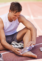 Image showing Injury, outdoor and man with water bottle on feet for exercise, running or workout pain at a sports stadium. Athlete person with muscle problem, accident or burnout while training for body fitness