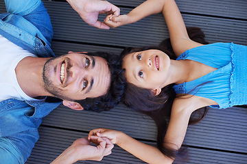 Image showing Holding hands, top view and relax father, happy kid or family bonding together for trust, support and solidarity. Fathers Day, floor and face of young kid, youth girl and dad lying on ground