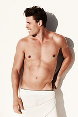 Image showing Sexy, muscle and body of a man in a towel while happy, handsome and clean. Strong, fitness and young male model posing shirtless on wall with smile, beauty and water drops after shower for art deco