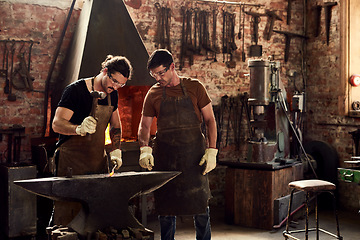 Image showing Welding, craftsmen working and in a metal workshop together with protection gear. Collaboration or teamwork, manufacturing and ppe with welder men with hammer work on iron at their workplace