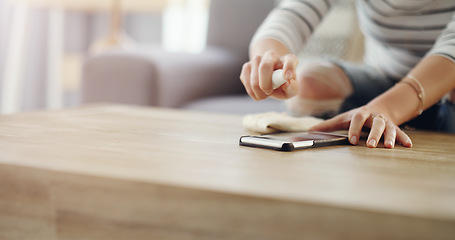 Image showing Woman, hands and cleaning screen of a phone on a wooden table in a home living room with spray bottle. Closeup of a female person with cloth and product to clean dirt, bacteria or dust on smartphone