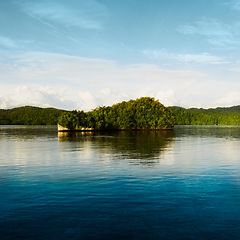 Image showing Water, island and natural lake with blue sky and clouds on calm, quiet or peaceful ocean and trees on land. Lakeside with tree in the distance and mockup space in nature view of scenic environment