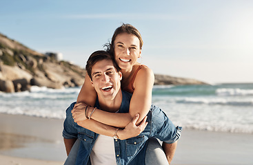 Image showing Young couple, portrait and piggyback at beach in summer sunshine with love, romance and bonding with travel. Man, woman and happy with hug, ocean waves and smile in nature, outdoor and vacation