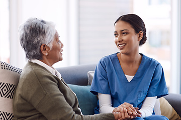 Image showing Communication, caregiver and elderly woman on lounge holding hands in living room for support. Care or healthcare, happy people and female nurse talking or consulting with a patient on a sofa.