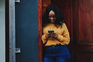 Image showing Door, phone and woman on social media, texting and happy while reading message in front of house. Smartphone, influencer and african female online for blog, networking or accommodation app review