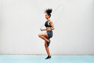 Image showing Jump, skipping rope and training with woman in stadium for sports, workout practice and cardio. Performance, health and body with female athlete jumping on track for strong, mockup space and exercise