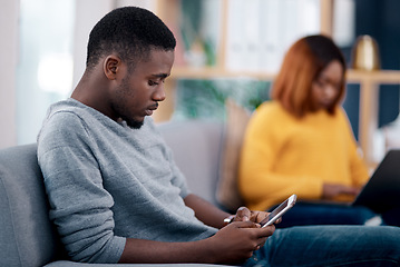 Image showing Relax, phone or technology addiction and a black man on the living room sofa of his home with his girlfriend on a blurred background. Mobile, contact and social media with a male person in a house