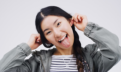 Image showing Portrait, funny face and ears with an asian woman in studio on a gray background looking silly or goofy. Comedy, comic and crazy with a playful young female person joking indoor for fun or humor