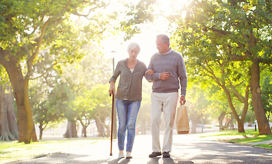 Image showing Senior couple, cane and walking outdoor at a park with a love, care and support for health and wellness. A elderly man and woman in nature for a walk, quality time and healthy marriage or retirement