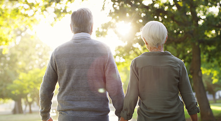 Image showing Senior couple, walking and outdoor at a park with a love, care and support from back. A elderly man and woman holding hands in nature for a walk, quality time and healthy marriage or retirement