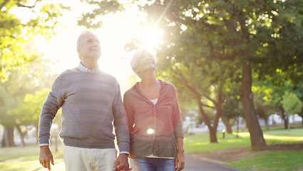 Image showing Senior couple, holding hands and walking outdoor at a park with love, care and support. A elderly man and woman in nature for a walk, quality time and hope for a healthy marriage or retirement