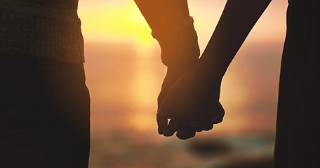 Image showing Holding hands, couple and sunset sky at beach with love on vacation, holiday or adventure. Man and woman silhouette outdoor to celebrate marriage, commitment and ocean travel or date in nature