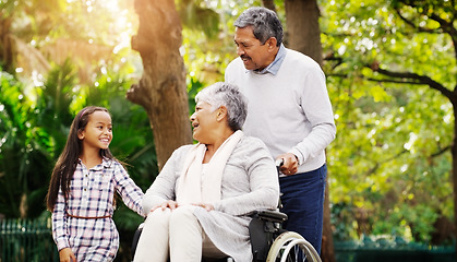 Image showing Grandparents, park and a senior woman in a wheelchair together with her husband and granddaughter. Disability, family or kids and a girl child bonding with her senior relatives in a natural garden