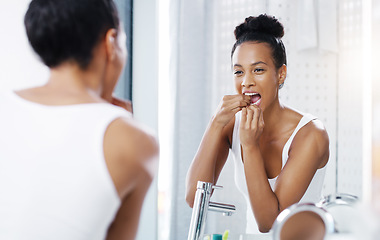 Image showing Woman flossing teeth in bathroom, mirror and oral hygiene, morning routine with product for dental health. Female person at home with grooming and self care, clean mouth with floss and wellness