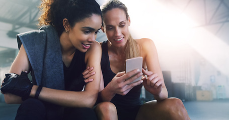 Image showing Fitness, phone and girl friends watching a video in a gym with women and smile from training. Social media app, mobile and female person in wellness, exercise and workout class taking a break