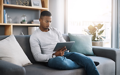 Image showing Remote work, tablet and man on sofa reading email, social media post or streaming video on subscription service. Search, scroll and internet, freelance worker checking website on couch in living room