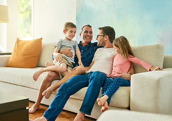 Image showing Gay parents, family hug and living room couch with dads and kids together with laugh and tickle. Parent love, bonding and care with father, papa and children in a home with a smile and lgbt people