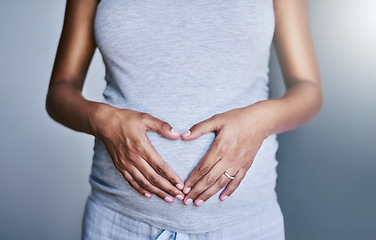 Image showing Pregnancy, woman and heart hands on her stomach for love, care and maternity in her house. Bonding, maternal and closeup of a pregnant female person holding her belly for motherhood at her home.