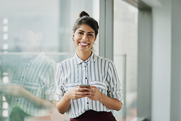 Image showing Business woman, portrait and phone with happiness at office window with a smile. Young female face employee and mobile connection of a worker feeling happy on social media and technology at company