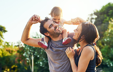 Image showing Family, dad and daughter on shoulders in park with mom, happiness or love in summer sunshine. Young couple, baby girl or laugh together for freedom, bond or holding hands for care, backyard or garden