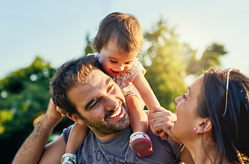 Image showing Family, father and daughter on shoulders in park with happy mom, love and summer sunshine. Young couple, baby girl or laugh together for freedom, bond and helping hand for care, backyard or garden