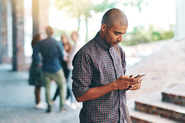 Image showing Young man, student and texting with smartphone on campus, university and reading on social media app. Guy, cellphone and web search outdoor with connectivity, blog and email communication on internet