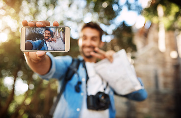 Image showing Man, phone screen and travel selfie outdoor in a city with holiday memory, smile and peace sign. Male person outdoor for adventure, journey or vacation photo and freedom with hand for emoji or icon