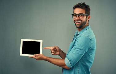 Image showing Happy man, tablet and pointing to mockup screen for advertising against a grey studio background. Portrait of male person smiling showing technology display, chromakey or copy space for advertisement