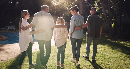 Image showing Back, hug and a family in a backyard for sunshine, summer and conversation. Happy, love and parents, grandparents and a child in a home garden with affection, walking and speaking during a visit