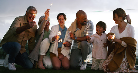 Image showing Outdoor, happy and family with fireworks, celebration and party with fun, backyard and cheerful together. Grandparents, mother and father with children, kids and happiness with sparklers and love